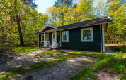 Finnisches Chalet-Holzhaus im Holiday Park De Wiltzangh, Niederlande, eingebettet in grüne Natur.