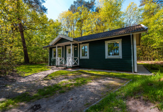 Finnish Chalet wooden cabin in Holiday park De Wiltzangh, Netherlands, surrounded by lush green trees.