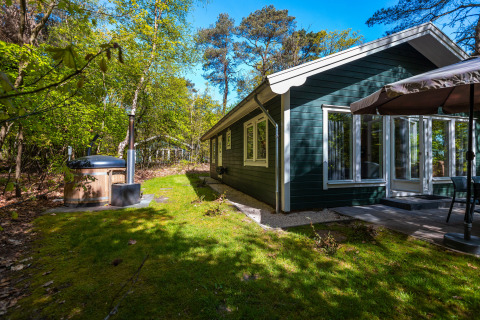 Chalet finlandés en Holiday Park De Wiltzangh, Países Bajos, con patio, jacuzzi exterior y bosques alrededor.