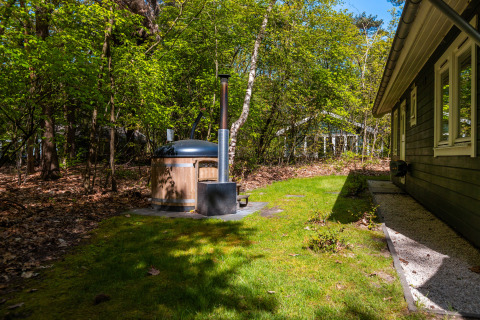 Træhytte omgivet af skov, med træbadekar ved siden af, på Holiday park De Wiltzangh i Holland.