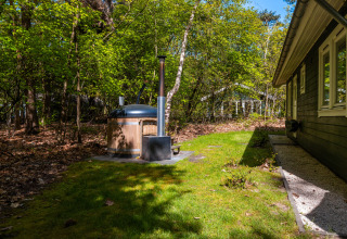 Fins chalet bij Holiday park De Wiltzangh, Nederland, met houten hottub in groene bostuin.