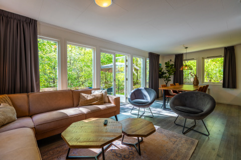 Woonkamer in Fins chalet bij vakantiepark De Wiltzangh in Nederland met bank, stoelen en eettafel.