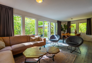 Woonkamer in Fins chalet bij vakantiepark De Wiltzangh in Nederland met bank, stoelen en eettafel.
