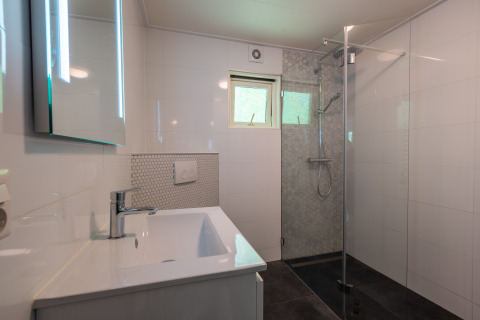 Moderne badkamer met douche, wastafel, spiegel en raam in Finnish Chalet op De Wiltzangh, Nederland.