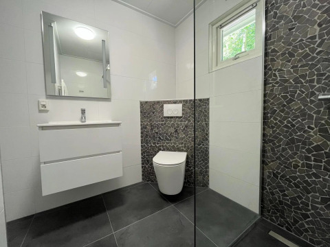 Moderne badkamer met witte meubels en donkere steenstrippen in een Finnish Chalet op Holiday park De Wiltzangh.