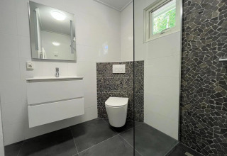Moderne badkamer met witte meubels en donkere steenstrippen in een Finnish Chalet op Holiday park De Wiltzangh.