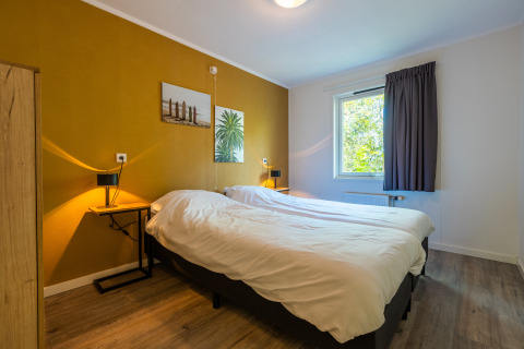 Slaapkamer in een Finnish Chalet bij vakantiepark De Wiltzangh in Nederland met een tweepersoonsbed.