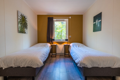 Chambre lumineuse avec deux lits simples, décor moderne et fenêtre dans Finnish Chalet à Holiday park De Wiltzangh.