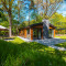 Lodge Hackfort moderne dans la forêt, grandes baies vitrées, terrasse et coin salon extérieur sous parasol.