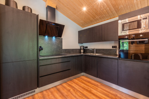 Modern black kitchen interior in the Hackfort lodge at Holiday park De Wiltzangh, Netherlands, with wood floor.