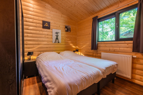 Gemütliches Schlafzimmer in der Hackfort-Lodge, Ferienpark De Wiltzangh, Niederlande, mit Holzwänden.