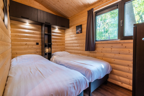 Slaapkamer met twee eenpersoonsbedden in Hackfort lodge in vakantiepark De Wiltzangh, Nederland, houten muren.