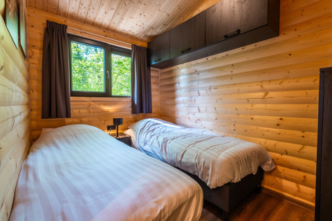 Slaapkamer met twee eenpersoonsbedden in een houten lodge van Hackfort, Holiday park De Wiltzangh, Nederland.