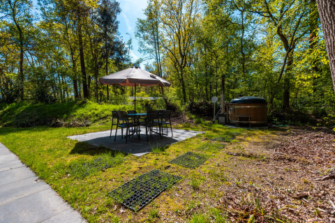 Terras met parasol, tuinstoelen en hottub bij lodge Hackfort, vakantiepark De Wiltzangh, Nederland.
