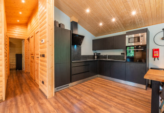 Moderne Küche in der Lodge 'Hackfort' im Ferienpark De Wiltzangh, mit Holzdetails und schwarzen Schränken.