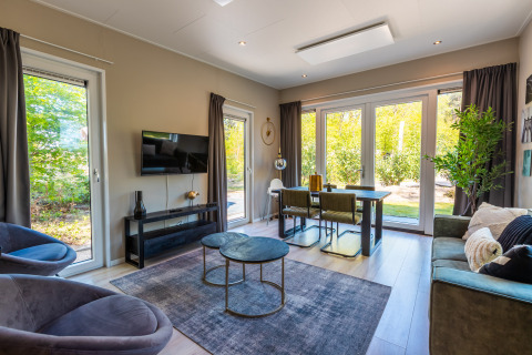 Helles, modernes Wohnzimmer in der Lodge Just Nature im Ferienpark De Wiltzangh, mit großen Fenstern und stilvollem Dekor.