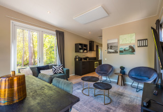Moderne woonkamer van de Just Nature-lodge in Holiday park De Wiltzangh, Nederland, met grote ramen en stijlvolle inrichting.