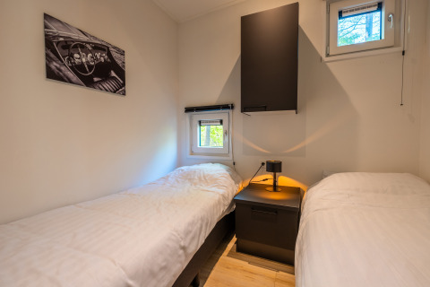 Schlafzimmer mit zwei Einzelbetten, Nachttisch und Fenstern im Lodge 'Just Nature' im De Wiltzangh Park, Niederlande.