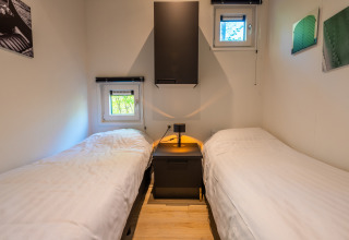 Zwei Einzelbetten mit Nachttisch im Just Nature-Lodge im Ferienpark De Wiltzangh in den Niederlanden.