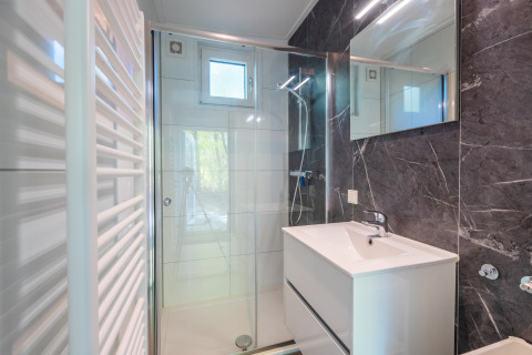 Salle de bain moderne avec douche, lavabo et miroir au lodge Just Nature, parc De Wiltzangh, Pays-Bas.