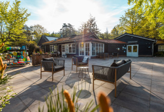 Sunny patio with lounge seating in front of Just Nature lodge at Holiday park De Wiltzangh, Netherlands.
