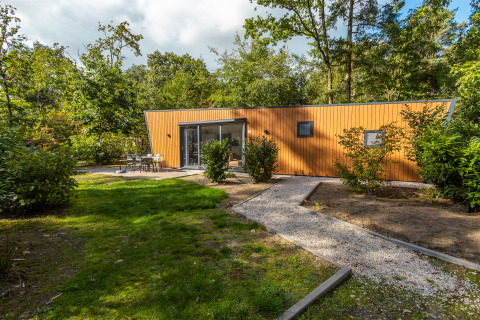Ein modernes Holzlodge bei Just Nature Hot tub, eingebettet in einen grünen, bewaldeten Garten.
