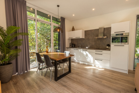Moderne keuken en eethoek met grote ramen en tuinzicht in de Just Nature-lodge, De Wiltzangh, Nederland.