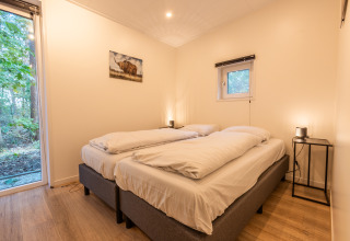 Lichte slaapkamer met twee eenpersoonsbedden, boszicht, minimalistisch bij Just Nature lodge in De Wiltzangh.