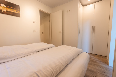 Dormitorio en Just Nature lodge, Holiday park De Wiltzangh, Países Bajos, con cama, armario y suelo de madera.