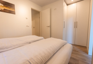 Slaapkamer in Just Nature-lodge, Holiday park De Wiltzangh, Nederland, met bed, kast en houten vloer.