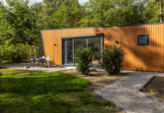 Udendørsfoto af Just Nature-lodge i ferieparken De Wiltzangh i Holland, omgivet af grønne træer.