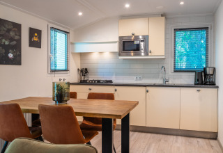 Cucina moderna e zona pranzo in un lodge al Holiday park De Wiltzangh, Paesi Bassi, con tavolo di legno.