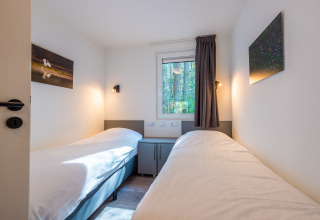 Tweepersoonskamer met lichte inrichting en bosuitzicht in Stuga lodge bij vakantiepark De Wiltzangh, Nederland.