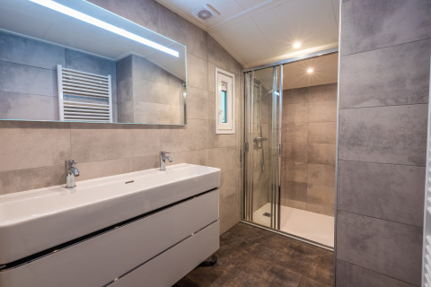 Salle de bain moderne avec double lavabo, grand miroir et douche à Stuga au parc De Wiltzangh, Pays-Bas.