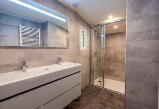 Bagno moderno con doppio lavandino, grande specchio e doccia alla Stuga di De Wiltzangh, Paesi Bassi.