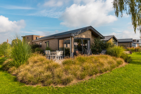 Lodge Velthorst moderne au Holiday park Aan de Maas, Pays-Bas, entouré d'un beau jardin verdoyant et plantes.