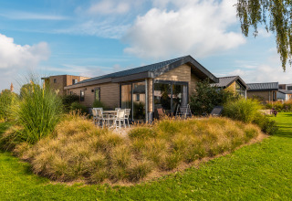 Lodge Velthorst moderne au Holiday park Aan de Maas, Pays-Bas, entouré d'un beau jardin verdoyant et plantes.