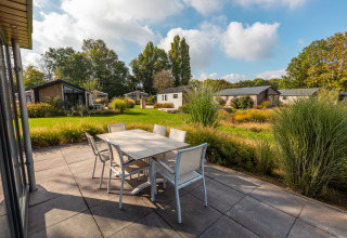 Terrasse mit Esstisch bei der Velthorst-Lodge im Ferienpark Aan de Maas, Niederlande, von Natur umgeben.