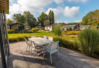 Terrasse mit Esstisch bei der Velthorst-Lodge im Ferienpark Aan de Maas, Niederlande, von Natur umgeben.