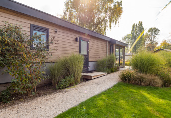Velthorst-Lodge im Ferienpark Aan de Maas, Niederlande, moderne Holzfassade und gepflegter Garten.