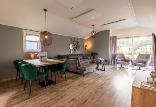 Salon et salle à manger modernes au lodge Velthorst du Holiday park Aan de Maas, avec grandes fenêtres et mobilier confortable.