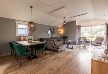 Modernes Wohnzimmer und Essbereich in der Velthorst-Lodge im Ferienpark Aan de Maas mit großen Fenstern und stilvoller Einrichtung.