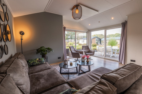 Soggiorno del lodge Velthorst al Holiday park Aan de Maas, Paesi Bassi, con divano e vista terrazza.