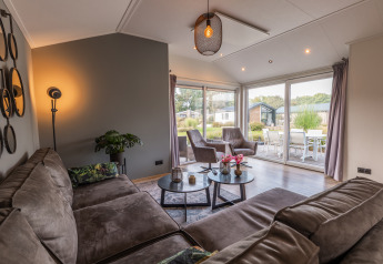 Wohnzimmer der Velthorst-Lodge im Holiday Park Aan de Maas, Niederlande, mit Sitzbereich und Terrasse.