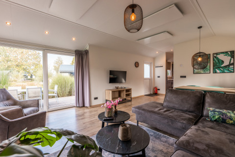 Living room in Velthorst lodge at Holiday park Aan de Maas, Netherlands, featuring modern decor and terrace view.