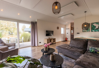 Wohnzimmer in der Velthorst-Lodge im Ferienpark Aan de Maas, Niederlande, mit moderner Einrichtung und Terrasse.