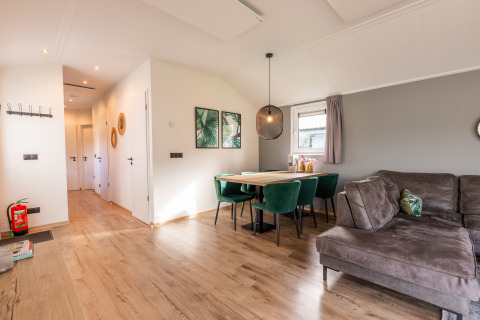 Modern Velthorst lodge living and dining area at Holiday Park Aan de Maas, Netherlands, with green chairs.