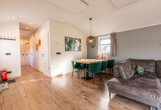 Moderne woonkamer en eethoek in lodge Velthorst op Holiday park Aan de Maas, Nederland, met groene stoelen.