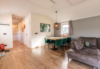 Moderne Lodge „Velthorst“ im Holiday Park Aan de Maas, Niederlande, mit Sofa und elegantem Essbereich.