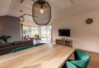 Modern living and dining area at Velthorst lodge, Holiday park Aan de Maas, Netherlands, with large windows.